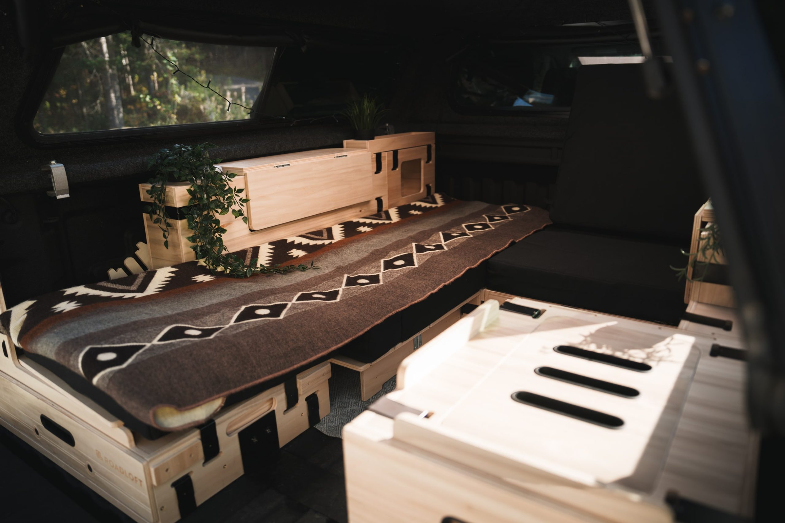 Roadloft minivan kit featuring a solo-mode layout with a bed and workspace table next to each other.