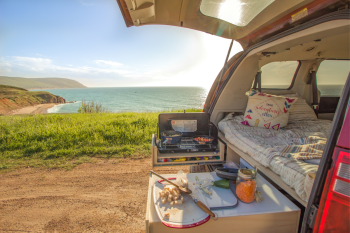 Hidden and ultra-functional kitchen in the Roadloft minivan kit with retractable sink, optimized drawers, and integrated cutting board for a compact and practical setup.