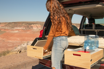 Swiveling kitchen shelf in the Roadloft minivan kit, providing easy access to storage while maximizing workspace.