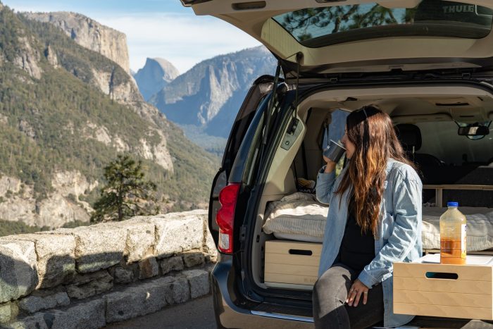a woman sitting in the back of a minivan with a conversion kit